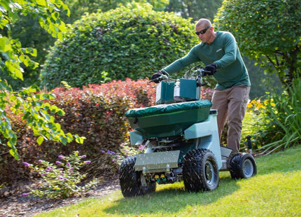 Operator on the PermaGreen Triumph spreader sprayer treating a lawn beside landscape beds